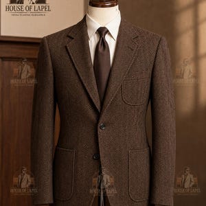 May include: A brown herringbone blazer featuring a notched lapel, two lower patch pockets, and one upper chest patch pocket. The blazer is worn over a cream-colored collared shirt with a solid dark brown necktie, displayed on a mannequin.