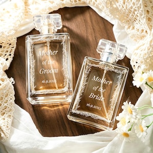 May include: Two rectangular glass perfume bottles with clear caps and spray nozzles. One bottle is engraved with "Mother of the Groom" and "16.9.2025", the other with "Mother of the Bride" and "16.9.2025". Both feature a delicate floral vine border.