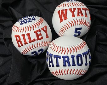 Può includere: Tre palline da baseball bianche con cuciture rosse. Le palline da baseball sono personalizzate con i nomi "Riley", "Wyatt" e "Patriots" in ricamo blu. Le palline da baseball hanno anche i numeri "32", "5" e "2024" ricamati.