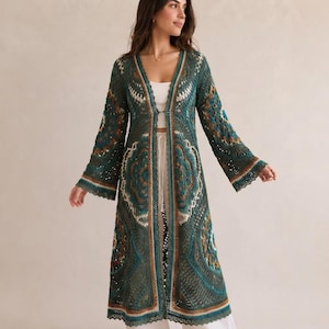Può includere: Un cardigan lungo all'uncinetto con apertura frontale e maniche lunghe, caratterizzato da un complesso motivo ispirato ai mandala nei toni del verde ottanio, verde bosco, crema e marrone. Il capo presenta maniche ampie e orlo smerlato.