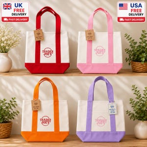 May include: Four canvas tote bags in red, pink, orange, and purple. Each bag features a white center panel with the Trader Joe's logo printed in the corresponding color, matching handles, and a solid colored base with a hanging product tag.