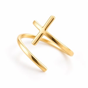 Könnte beinhalten: Ein goldfarbener offener Ring mit polierter Oberfläche und einem kreuzförmigen Designelement. Das Band ist glatt und geschwungen, um eine offene Struktur zu bilden, wobei das Kreuz an einem Ende des Metallbandes positioniert ist.