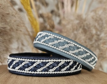May include: Two leather bracelets with silver braided trim. One bracelet is black and the other is a light blue-gray.