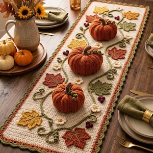 May include: A rectangular cream-colored crochet table runner featuring three dimensional orange pumpkins, green vine accents, and various autumn-colored leaves in shades of yellow, orange, and green, finished with a scalloped green border edge.