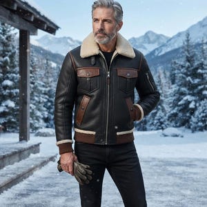 May include: A black leather jacket with a cream-coloured shearling collar, brown leather pocket flaps, and brown ribbed cuffs. The jacket features a front zip closure, two chest pockets with snap buttons, and two lower pockets with brown leather trim.