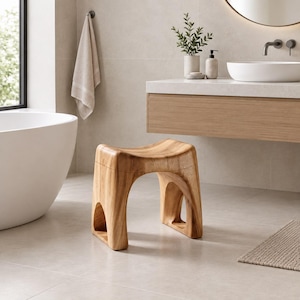 Può includere: Uno sgabello in legno marrone chiaro con una seduta curva e liscia e quattro gambe arcuate. Lo sgabello presenta una venatura del legno naturale e una costruzione solida, progettata con spazi aperti tra le gambe per un aspetto stabile ed equilibrato.