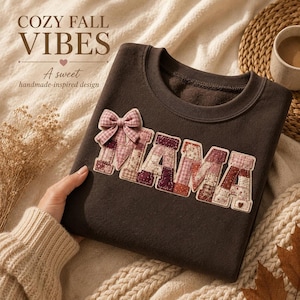 Puede incluir: Una sudadera de cuello redondo color marrón oscuro con la palabra MAMA en letras grandes acolchadas estilo patchwork, con varios patrones florales y de cuadros en rosa, burdeos y crema. Un pequeño lazo de cuadros vichy rosa adorna la primera M.