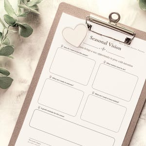 May include: A white paper planner sheet titled Seasonal Vision, Part of The Gentle Planner, clipped to a brown clipboard. The sheet features five rectangular boxes for writing, with prompts including How do I want to feel this season and What matters most to me.