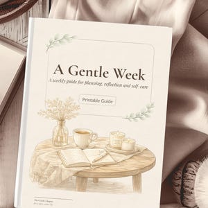 Op de afbeelding: Een boekcover in zachte tinten met de titel A Gentle Week: A weekly guide for planning, reflection and self-care. De illustratie toont een houten tafel met een open dagboek, een pen, een kopje thee, twee kaarsen en een vaas met bloemen.