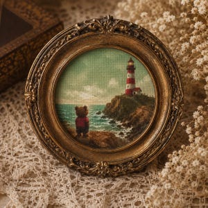 May include: A circular painting in an ornate, antique gold-toned frame depicting a small bear in a red shirt standing on a rocky cliff overlooking a sea with a red and white striped lighthouse on the horizon under a soft, cloudy sky.