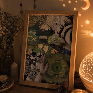 Puede incluir: Una impresión de collage enmarcada rectangular que presenta una mezcla de imágenes que incluyen cisnes blancos, follaje verde, elementos florales, una mano y un patrón geométrico circular. La obra contiene un pequeño globo de texto.