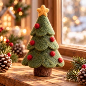 May include: A needle-felted green Christmas tree ornament with a yellow star topper and small red felted ball decorations. The tree has a layered, scalloped design and a brown felted base, standing upright as a decorative tabletop piece.