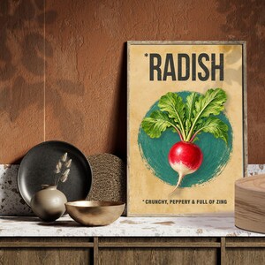 May include: A rectangular wall art print featuring a botanical illustration of a red radish with green leaves centered on a teal circle. The text RADISH appears at the top, and the text CRUNCHY, PEPPERY & FULL OF ZING appears at the bottom.