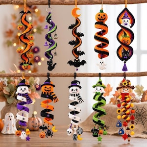 May include: Ten hanging crochet ornaments featuring Halloween themes including pumpkins, ghosts, bats, cats, skeletons, and sunflowers. Each ornament has a spiral design with various small charms attached, suspended from a wooden branch.