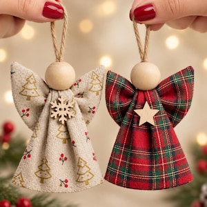 May include: Two hanging angel ornaments with wooden bead heads and jute twine loops. One angel features a beige fabric with gold Christmas tree and red berry prints and a wooden snowflake. The other features red and green plaid fabric and a wooden star.