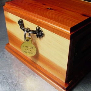 May include: A wooden box with a brass handle and a brass tag that reads "I AM LOST CALL 981 790 3741".