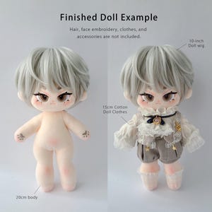 K&ouml;nnte beinhalten: Eine 20 cm gro&szlig;e Pl&uuml;schpuppe mit heller Haut, braunen Augen und kurzem grauen Haar. Der Text lautet: Finished Doll Example. Hair, face embroidery, clothes, and accessories are not included. Beschriftungen weisen auf 10-inch doll wig und 15cm cotton doll clothes hin.
