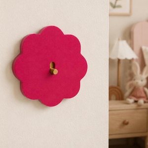 Op de afbeelding: Een fel magenta wandcontactdoosafdekplaat in de vorm van een geschulpte bloem. De plaat is voorzien van een centrale verticale rechthoekige uitsparing met een kleine, cilindrische messingkleurige tuimelschakelaar in het midden.