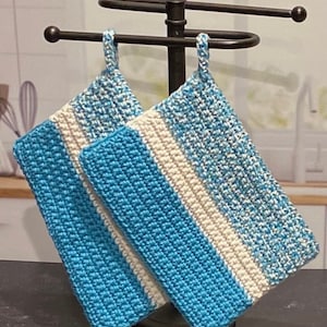 May include: Two blue and white striped crocheted pot holders hanging on a black metal pot holder stand.