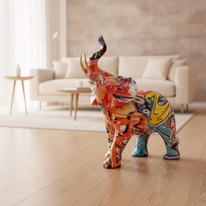 Peut inclure: Une figurine d'éléphant debout arborant un motif graffiti multicolore et vibrant sur tout le corps. La sculpture présente une trompe levée et des défenses dorées proéminentes, avec des éclats audacieux d'orange, de rouge, de bleu et de jaune.