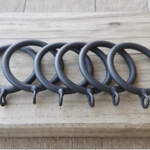 May include: Six black metal curtain rings with a hook on each ring.