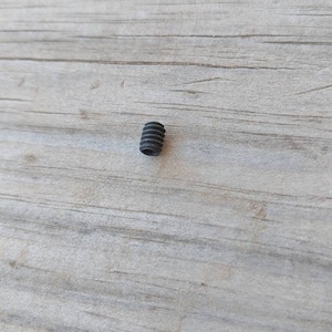 May include: A small black screw with a threaded shaft.