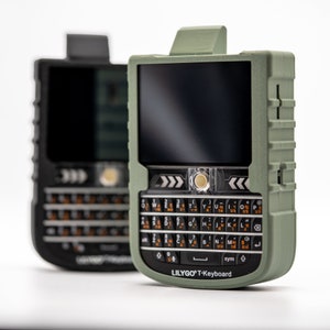 May include: Two rugged, olive green and black smartphones with physical keyboards. The front phone has a screen, a keyboard with white and orange keys, and the text "LILYGO T-Keyboard". The phones are on a white background.