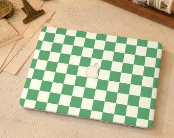 Könnte beinhalten: Eine Laptop-Hülle mit einem sich wiederholenden grün-weißen Schachbrettmuster, das die gesamte Oberseite bedeckt. Das Design enthält einen mittigen Ausschnitt, der das silberne Apple-Logo freilässt und ein gleichmäßiges Raster beibehält.