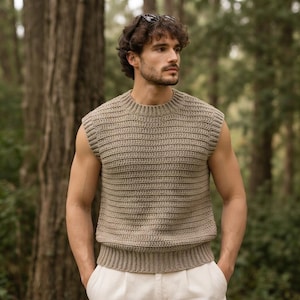 Könnte beinhalten: Eine beigefarbene ärmellose Strickweste mit horizontaler Rippenstruktur, Rundhalsausschnitt und einem eng anliegenden Rippensaum. Das Kleidungsstück ist durchgehend mit einem einheitlichen Strickmuster gefertigt und bietet eine strukturierte Optik.