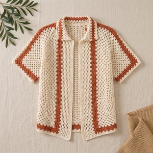 Peut inclure: Une chemise en crochet à manches courtes avec un design ouvert sur le devant et un col. Le vêtement est confectionné en fil couleur crème avec des rayures verticales orange rouille le long de la patte de boutonnage et des manches.