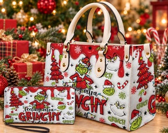 May include: A white handbag and matching rectangular wallet featuring a repeating pattern of the Grinch, red Christmas trees, candy canes, and snowflakes. The text "feeling extra GRINCHY" is printed in red and black on both items.