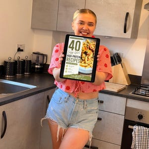 K&ouml;nnte beinhalten: Ein digitales Tablet, das ein Kochbuch-Cover mit dem Titel 40 Lazy Girl HIGH-PROTEIN RECIPES UNDER 500 CALORIES anzeigt, mit einem Foto von Nudeln mit Tomaten und Kr&auml;utern sowie dem Text Cook with Chloe am unteren Bildschirmrand.