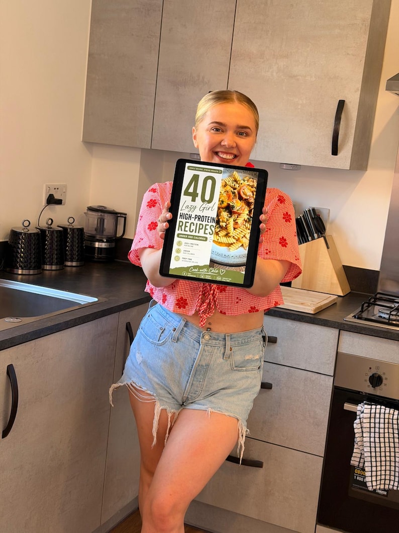 K&ouml;nnte beinhalten: Ein digitales Tablet, das ein Kochbuch-Cover mit dem Titel 40 Lazy Girl HIGH-PROTEIN RECIPES UNDER 500 CALORIES anzeigt, mit einem Foto von Nudeln mit Tomaten und Kr&auml;utern sowie dem Text Cook with Chloe am unteren Bildschirmrand.