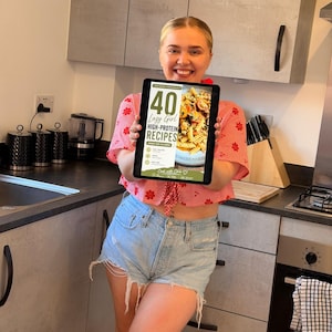 K&ouml;nnte beinhalten: Ein digitales Tablet, das ein Kochbuch-Cover mit dem Titel 40 Lazy Girl High-Protein Recipes Under 500 Calories anzeigt, mit einem Foto von Pasta mit Tomaten und Kr&auml;utern sowie dem Text Cook with Chloe am unteren Bildschirmrand.