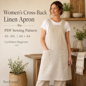 Op de afbeelding: Een beige linnen schort met gekruiste rugbanden en twee grote voorzakken. De tekst luidt: Women's Cross-Back Linen Apron, PDF Sewing Pattern, XS-3XL | A0 + A4, Confident Beginner, SewFoundry. Het schort wordt gedragen over een wit t-shirt.