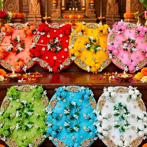 Può includere: Sette dischi circolari in tessuto nei colori arancione, rosso, giallo, rosa, verde, blu e bianco, decorati con fiori artificiali abbinati, decorazioni metalliche dorate e piccoli accenti floreali bianchi disposti in un motivo circolare.