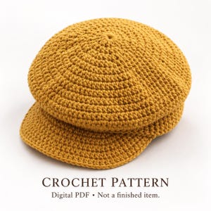 Peut inclure: Une casquette gavroche en crochet jaune moutarde avec une calotte arrondie et une visière courte et rigide. Le texte en dessous indique : CROCHET PATTERN Digital PDF • Not a finished item. Le bonnet présente un motif de mailles dense.