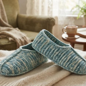 May include: A pair of teal and cream variegated yarn slippers featuring a ribbed crochet texture. The slippers have a rounded toe design and a low-cut opening, showcasing a consistent knit pattern throughout the exterior of the footwear.