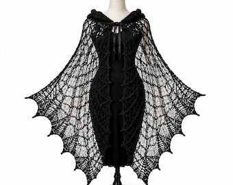 May include: A black crochet cape featuring an intricate web-like pattern with a pointed, scalloped hemline. The garment includes an attached hood and a thin ribbon tie closure at the neck, displayed on a mannequin wearing a black dress.