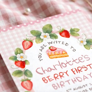 Puede incluir: Una tarjeta de invitaci&oacute;n rectangular con un borde de cuadros vichy rosa y blanco. El centro presenta una corona de fresas, un trozo de pastel y el texto: YOU ARE INVITED TO Charlotte's BERRY FIRST BIRTHDAY 5TH AUGUST 2026.