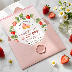 Puede incluir: Un sobre rosa que contiene una tarjeta de invitaci&oacute;n de cumplea&ntilde;os con un borde de cuadros vichy rosa claro. La tarjeta presenta una corona de fresas en acuarela, un trozo de pastel y el texto: YOU ARE INVITED TO Charlotte's BERRY FIRST BIRTHDAY.