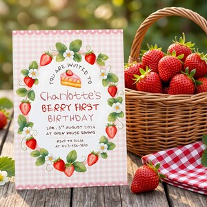 Puede incluir: Una tarjeta de invitaci&oacute;n rectangular con borde de cuadros vichy rosa, con una ilustraci&oacute;n de una corona de fresas y flores. El texto dice: YOU ARE INVITED TO Charlotte's BERRY FIRST BIRTHDAY 2PM 5TH AUGUST 2026 AT OPEN HOUSE DINING RSVP TO JULIA AT +123-456-7890.