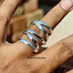 May include: A set of three polished silver rings worn together on a finger. The rings feature a smooth, rounded, and reflective surface with a simple band design. The text RaiSilverJewelers is visible at the bottom of the image area.