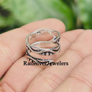 May include: A silver bypass ring featuring an oxidized finish with embossed dot and line patterns along the band. The metal surface displays a weathered texture, and the interior of the band is clearly stamped with the hallmark 925 for silver.