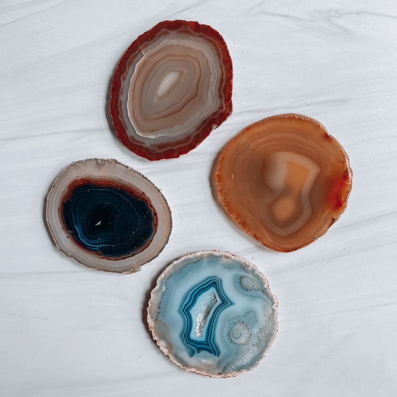 Peut inclure: Quatre sous-verres en agate de diff&eacute;rentes couleurs et motifs. Les sous-verres sont ronds et ont une finition naturelle et polie. Les couleurs comprennent le brun, l'orange, le bleu et le noir.