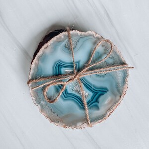Peut inclure: Deux sous-verres en agate avec un motif bleu et blanc li&eacute;s ensemble avec de la ficelle. Les sous-verres sont ronds et ont un aspect naturel et organique.