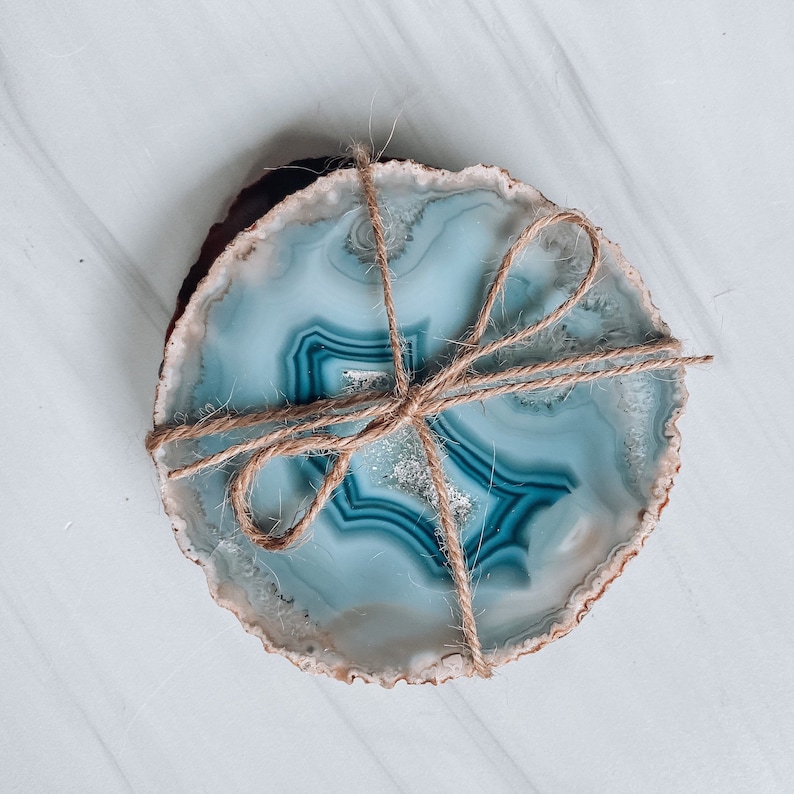 Peut inclure: Deux sous-verres en agate avec un motif bleu et blanc li&eacute;s ensemble avec de la ficelle. Les sous-verres sont ronds et ont un aspect naturel et organique.