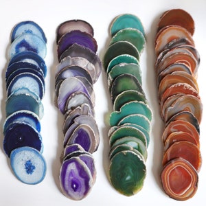 Peut inclure: Un ensemble de trois sous-verres en agate de couleur bleue, violette et orange. Chaque sous-verre est compos&eacute; d'une pile de fines tranches d'agate, cr&eacute;ant un effet de superposition. Les tranches d'agate sont polies et ont un aspect naturel et organique.