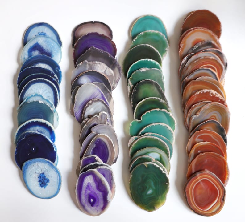 Peut inclure: Un ensemble de trois sous-verres en agate de couleur bleue, violette et orange. Chaque sous-verre est compos&eacute; d'une pile de fines tranches d'agate, cr&eacute;ant un effet de superposition. Les tranches d'agate sont polies et ont un aspect naturel et organique.