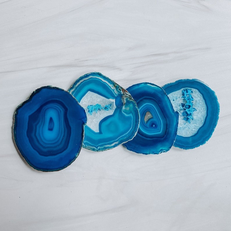 Peut inclure: Quatre sous-verres en agate bleue avec des motifs blancs et bleus. Les sous-verres sont ronds et ont une finition naturelle et polie.